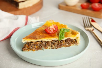 Photo of Piece of delicious pie with minced meat, tomato and basil served on light marble table, closeup
