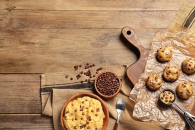 Bowl with dough and uncooked chocolate chip cookies on wooden table, flat lay. Space for text