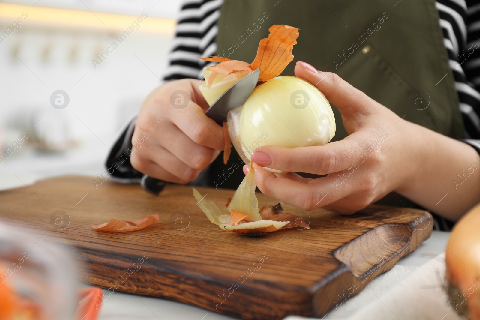 Photo of Woman peeling fresh onion with knife at white marble table indoors, closeup