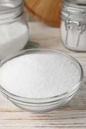 Photo of Granulated sugar in glass bowl on white wooden table, closeup