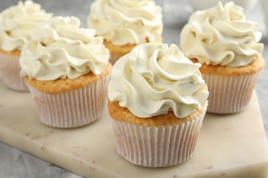 Photo of Tasty cupcakes with vanilla cream on grey table, closeup