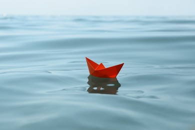 Photo of Orange paper boat floating on water surface