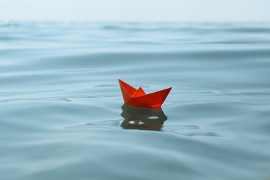 Orange paper boat floating on water surface