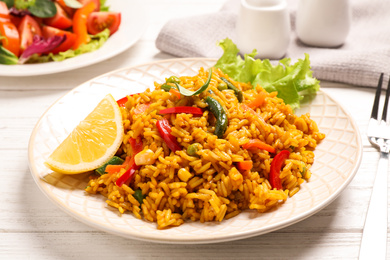 Delicious rice pilaf with vegetables on white wooden table