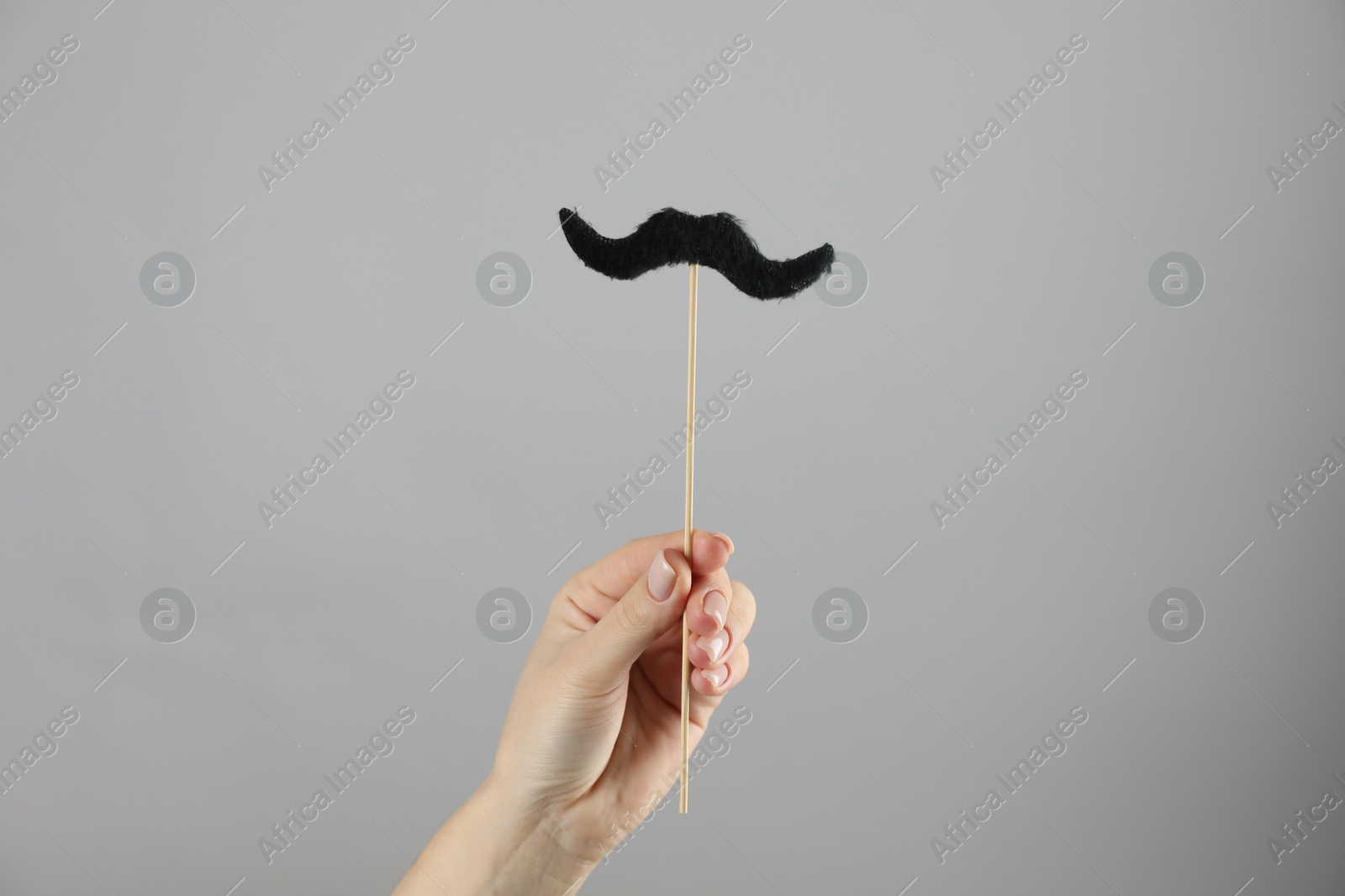 Photo of Woman with fake paper mustache on gray background, closeup