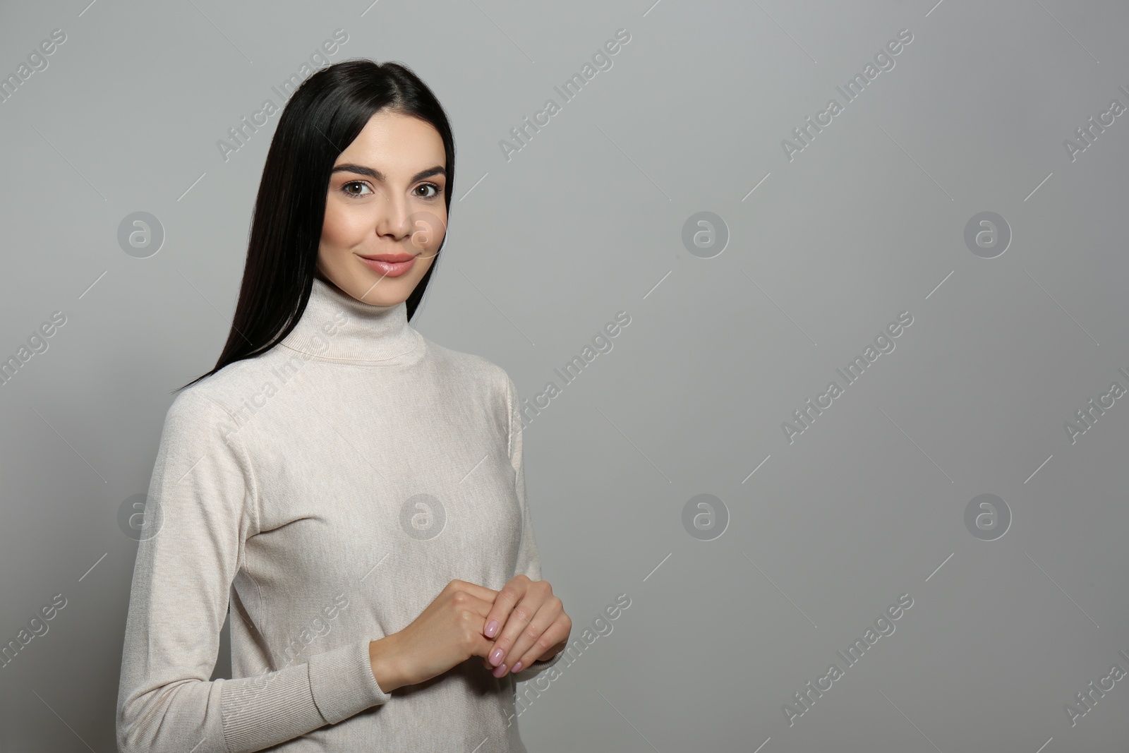 Photo of Portrait of happy young woman with beautiful black hair and charming smile on light grey background, space for text