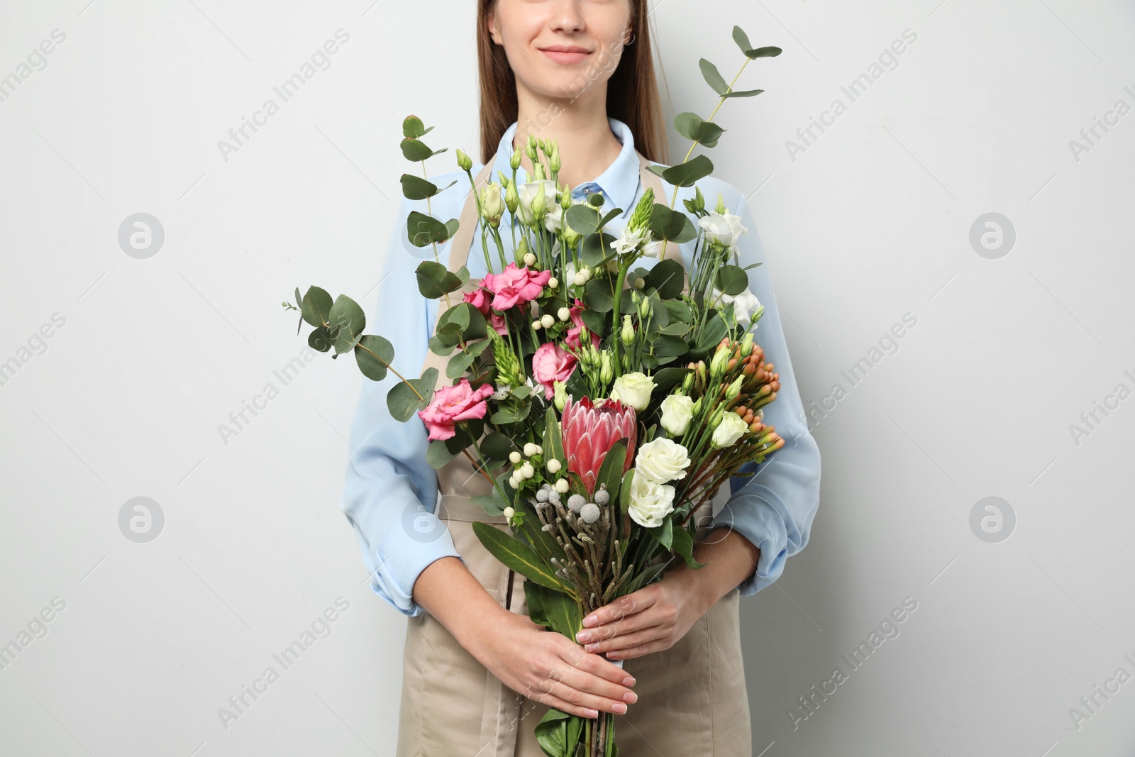 Photo of Florist with beautiful bouquet on light background, closeup