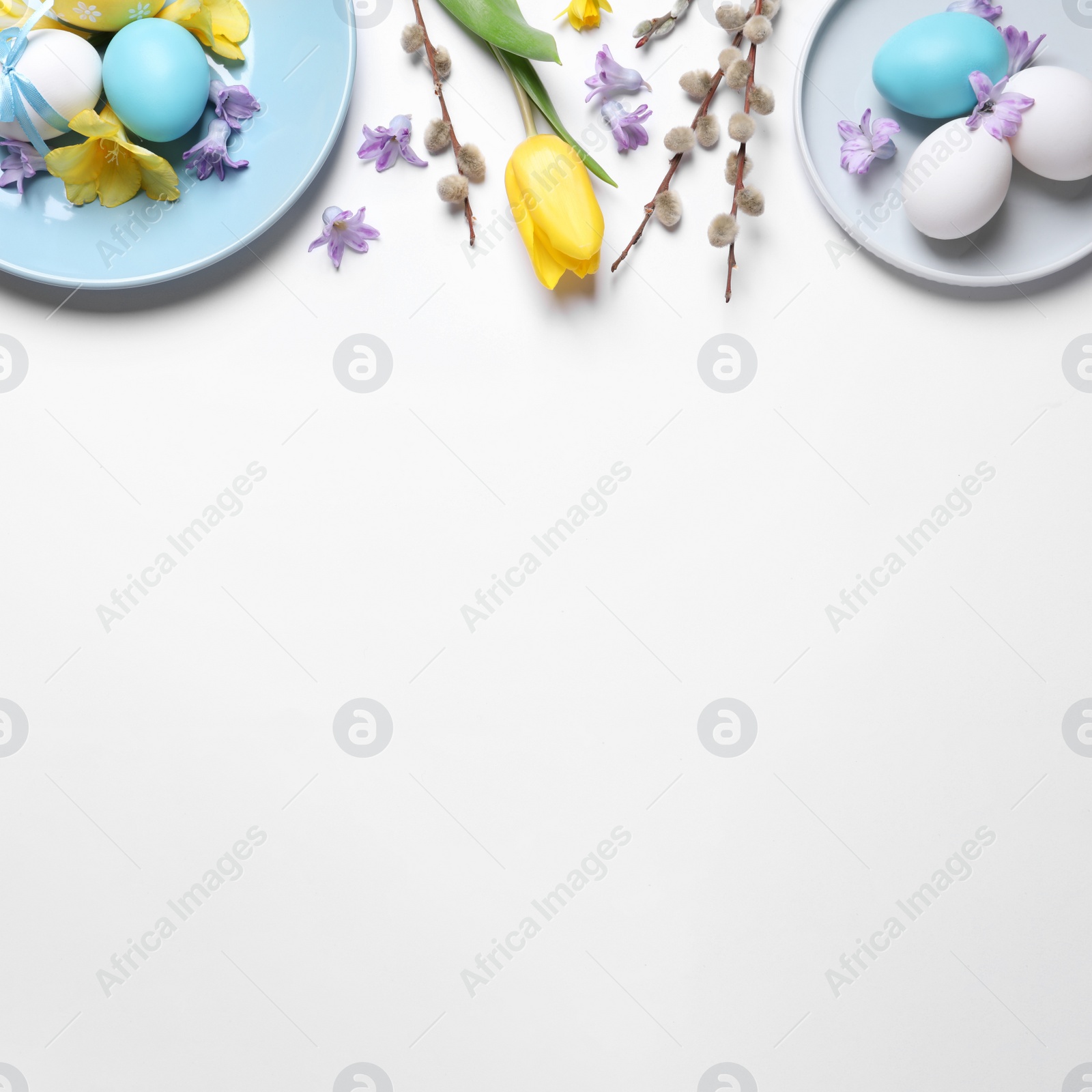 Photo of Festive Easter table setting with painted eggs and floral decor on white background, flat lay. Space for text