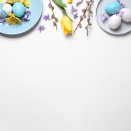 Festive Easter table setting with painted eggs and floral decor on white background, flat lay. Space for text