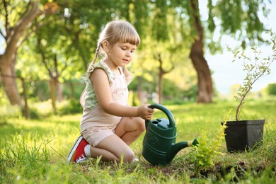 Photo of Cute little girl watering tree in garden
