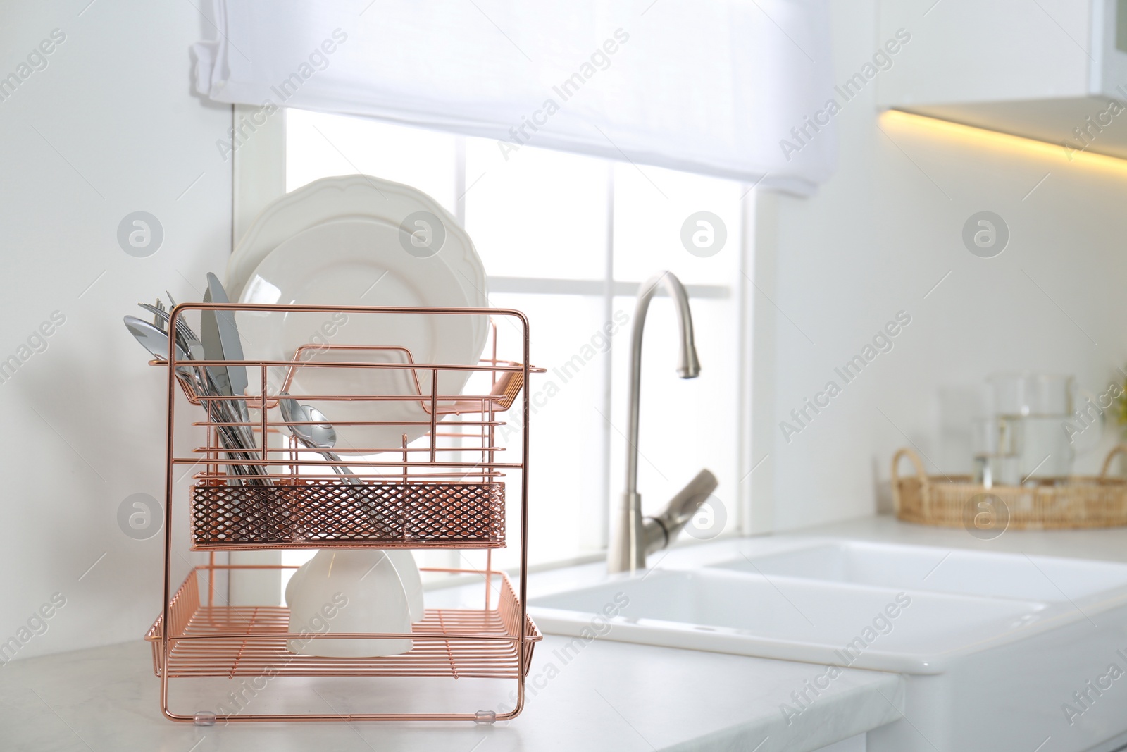 Photo of Clean dishes on drying rack in modern kitchen interior