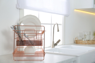 Clean dishes on drying rack in modern kitchen interior