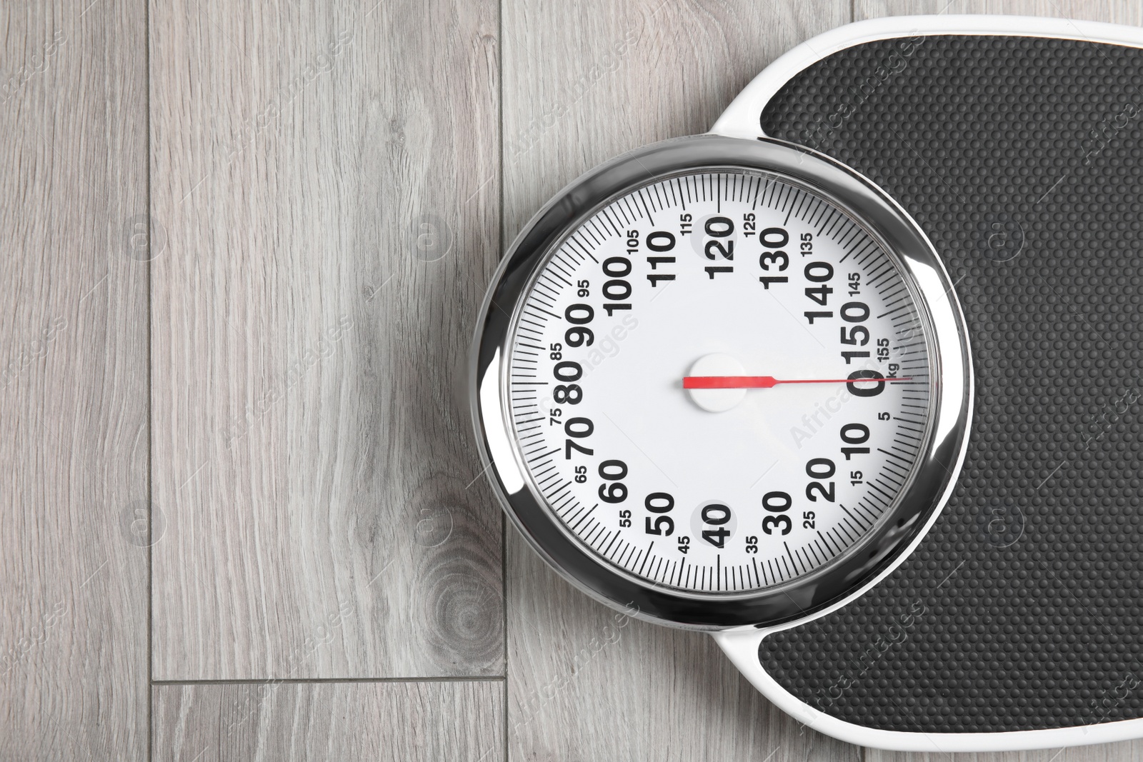 Photo of Modern scales on wooden floor, top view with space for text