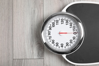 Modern scales on wooden floor, top view with space for text