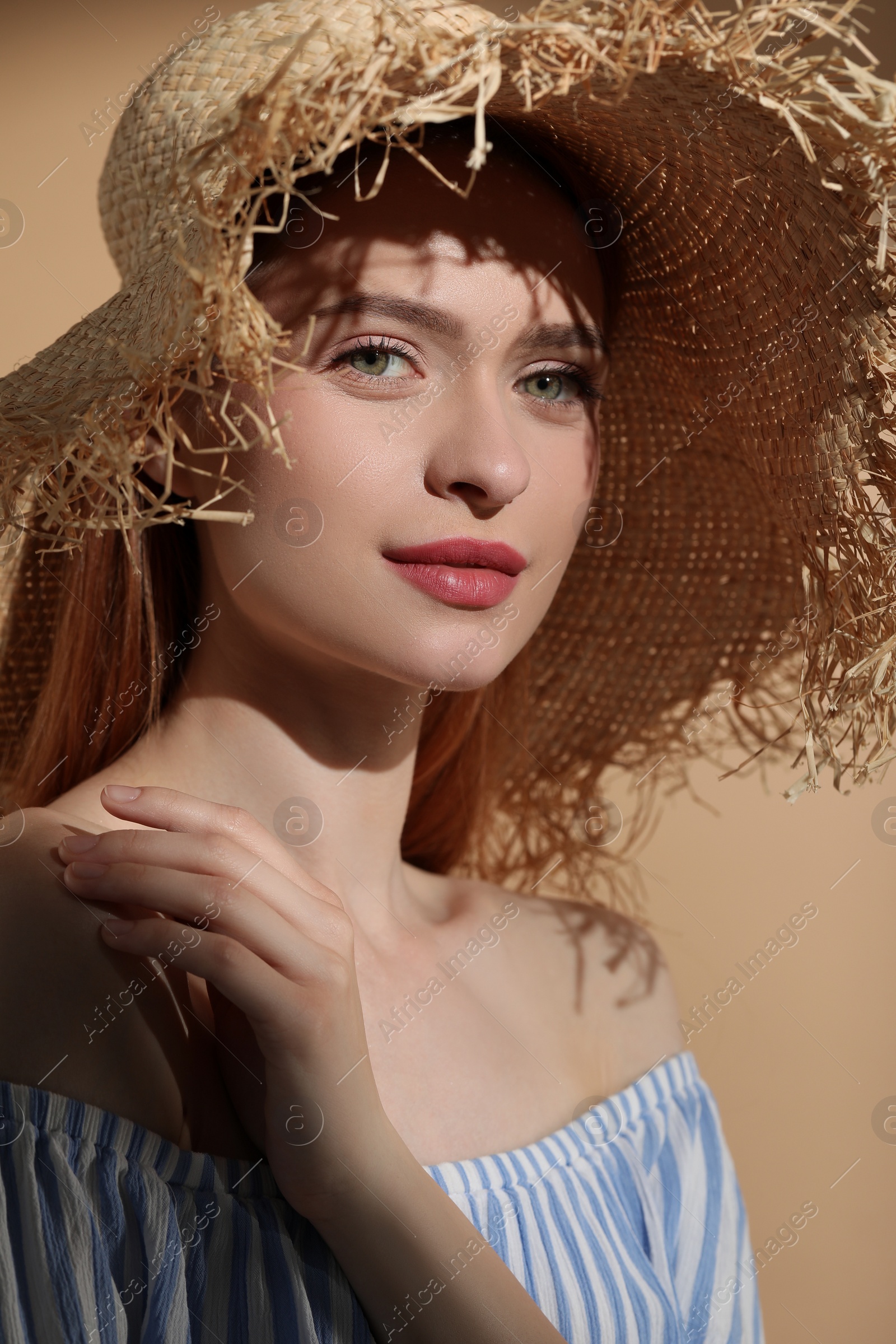 Photo of Beautiful young woman in sunlight on beige background