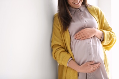 Photo of Young pregnant woman in casual clothes on light background