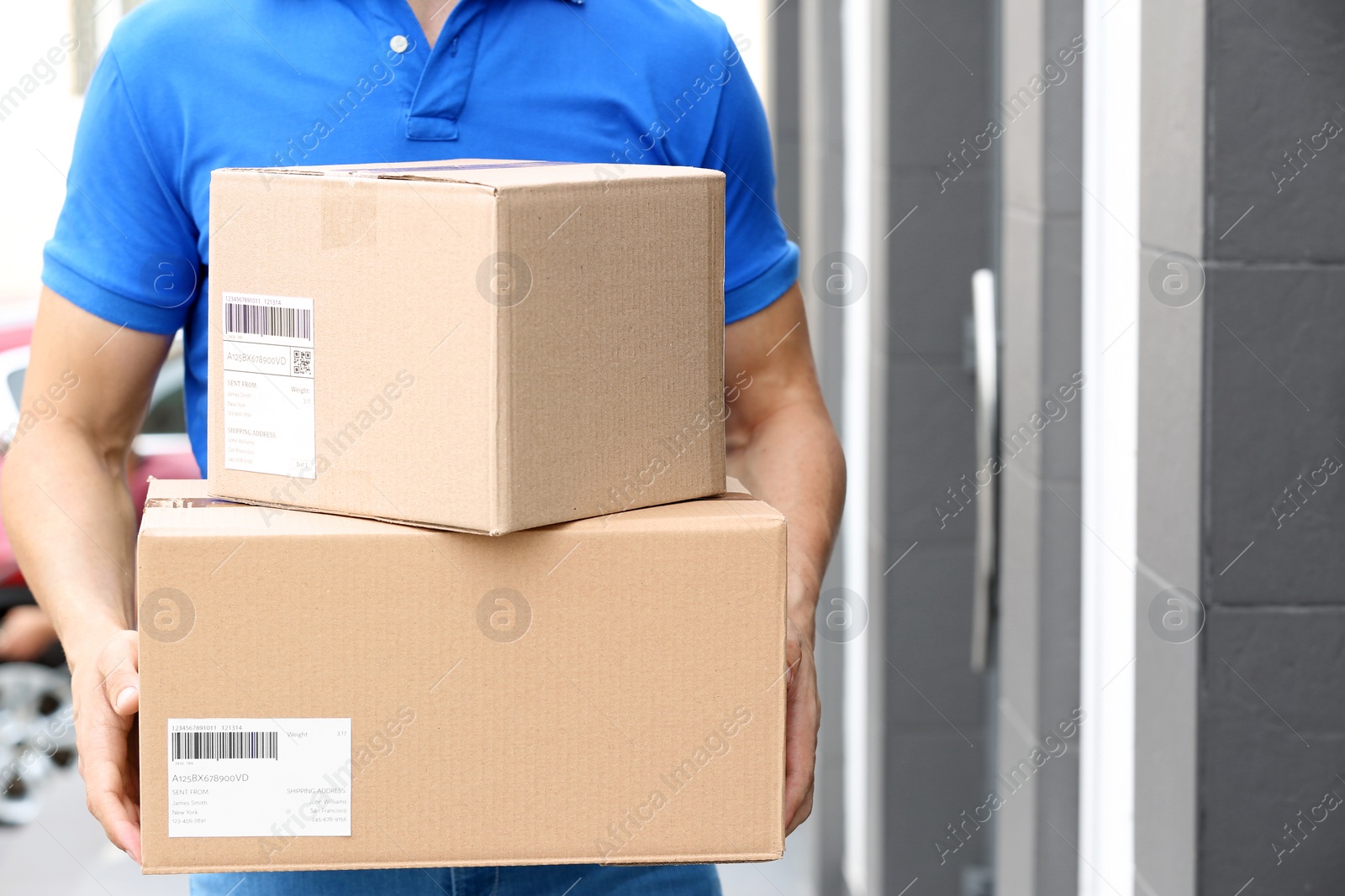 Photo of Delivery service courier with parcels in hands outdoors