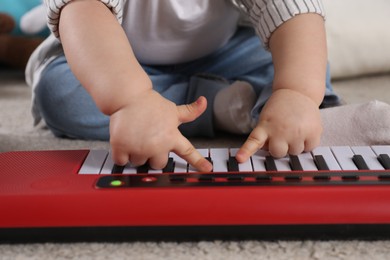 Photo of Little child playing toy piano indoors, closeup