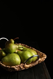 Photo of Tray with ripe pears on wooden table against dark background. Space for text