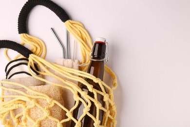 Photo of Fishnet bag with different items on white background, top view and space for text. Conscious consumption