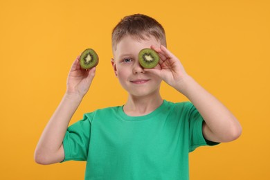 Photo of Boy with fresh kiwi on orange background