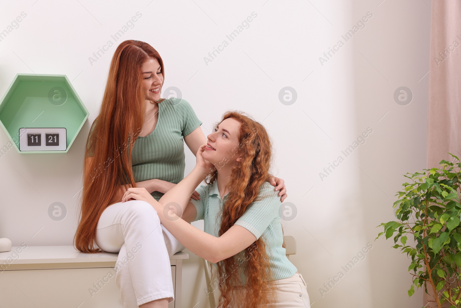 Photo of Portrait of beautiful young redhead sisters at home. Space for text copy