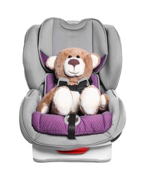 Photo of Teddy bear in child safety car seat on white background