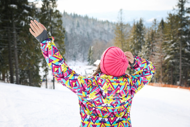Photo of Young woman at mountain resort, back view. Winter vacation
