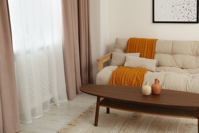 Photo of Living room with pastel window curtains, wooden table and sofa