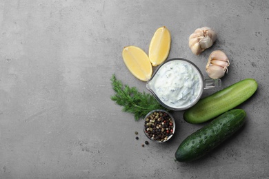 Photo of Cucumber sauce with garlic, lemon, dill and pepper on grey background, top view. Space for text