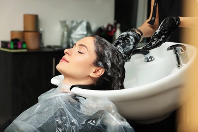 Hairdresser rinsing out dye from woman's hair in beauty salon