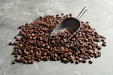 Photo of Roasted coffee beans and scoop on grey background