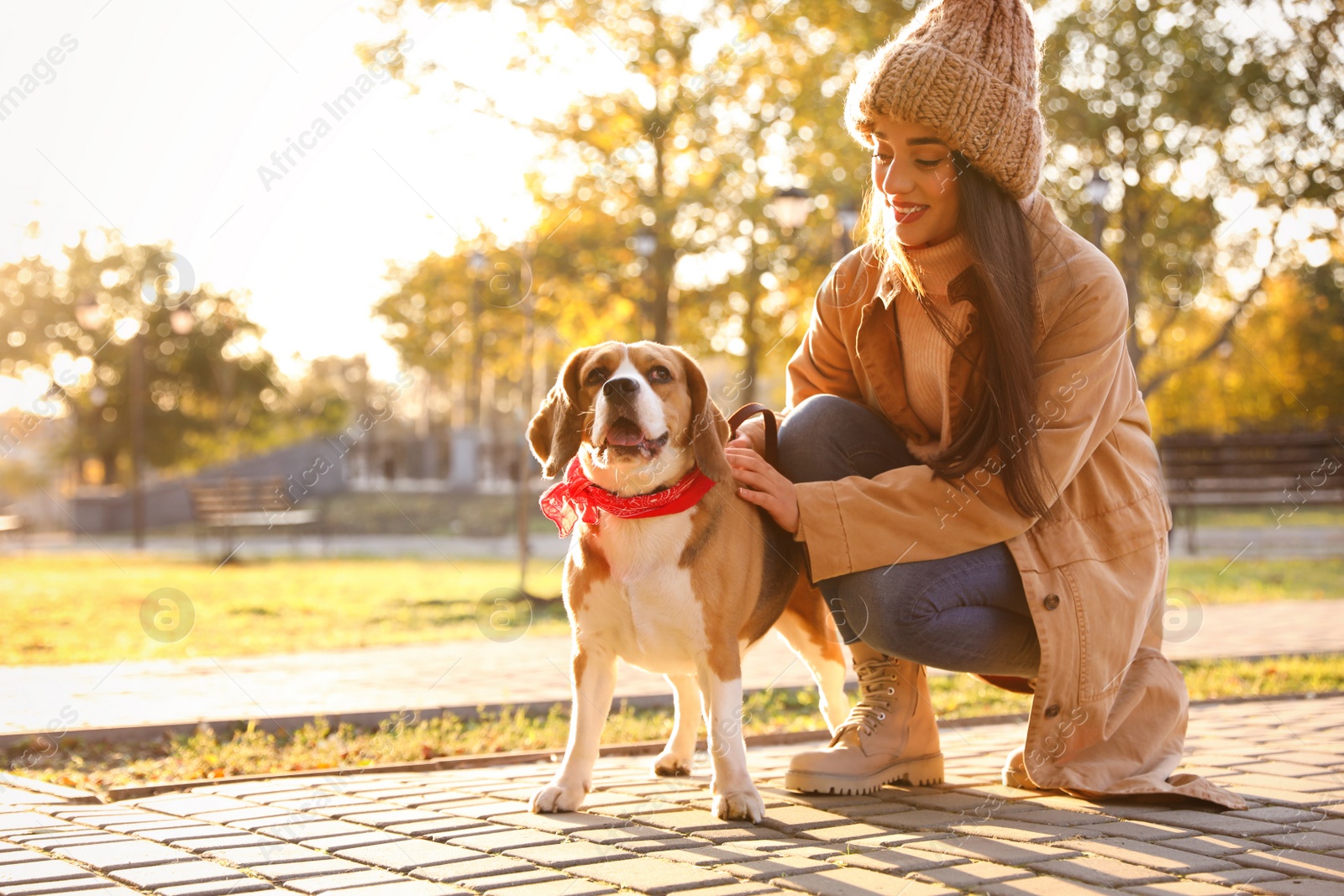 Photo of Woman walking her cute Beagle dog in autumn park