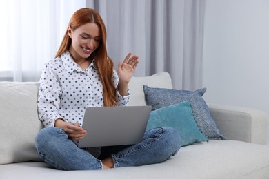 Woman waving hello during video chat via laptop at home, space for text