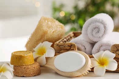 Composition with different spa products and plumeria flowers on white table indoors, closeup