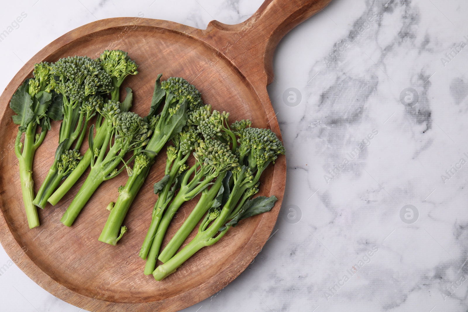 Photo of Fresh raw broccolini on white marble table, top view and space for text. Healthy food