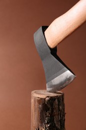 Photo of Metal ax in wooden log on brown background