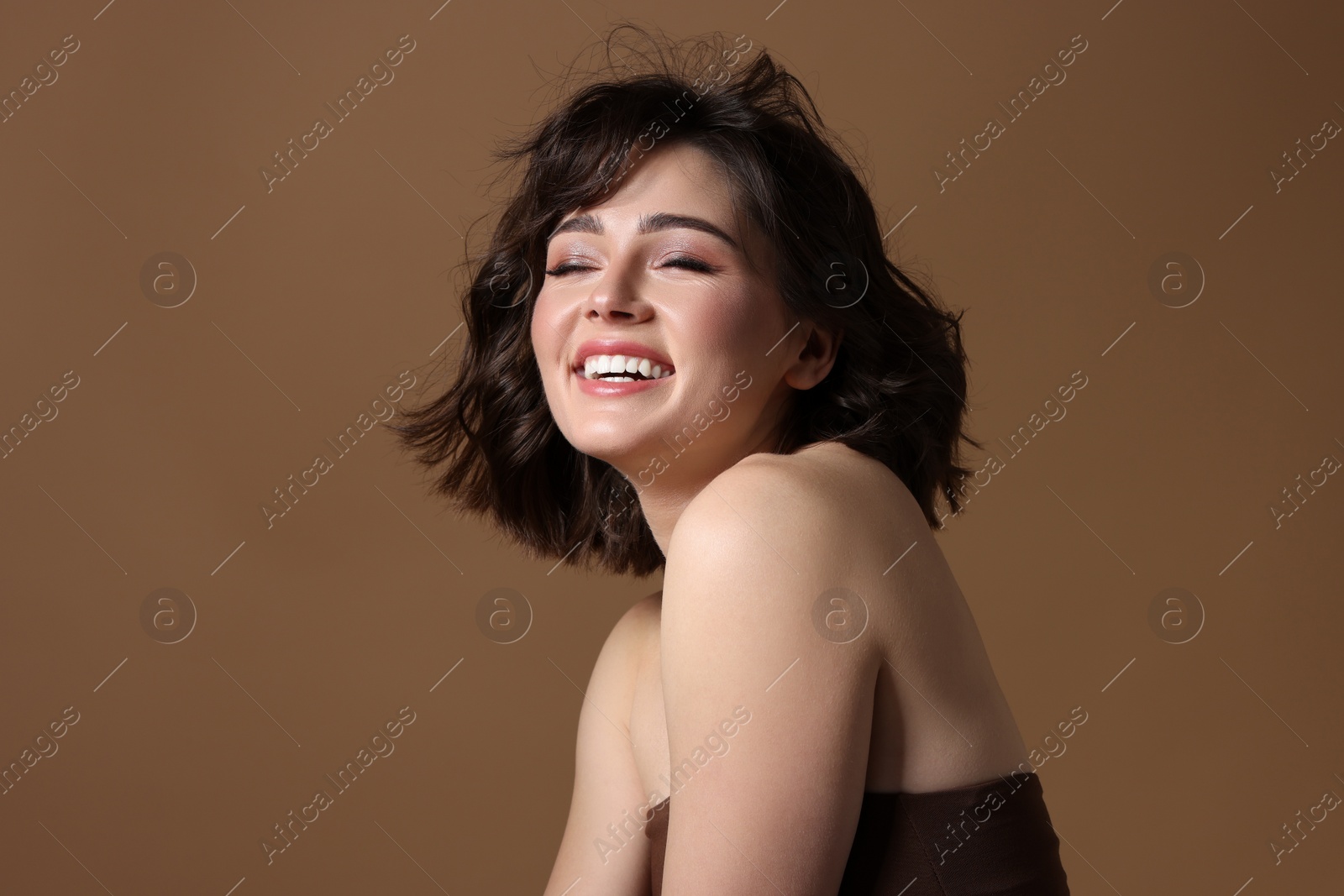 Photo of Portrait of beautiful young woman with wavy hairstyle on brown background