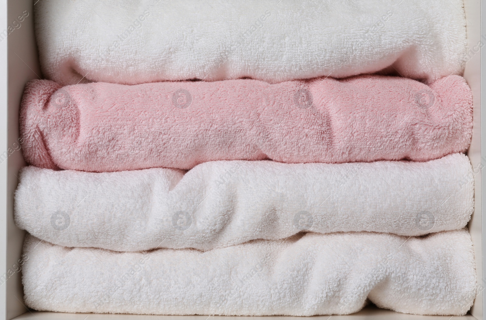 Photo of Colorful towels on shelf, closeup. Bathroom supplies