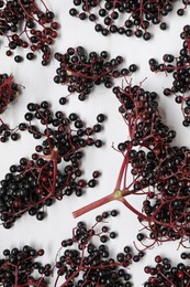 Photo of Bunches of ripe elderberries on white marble table, flat lay