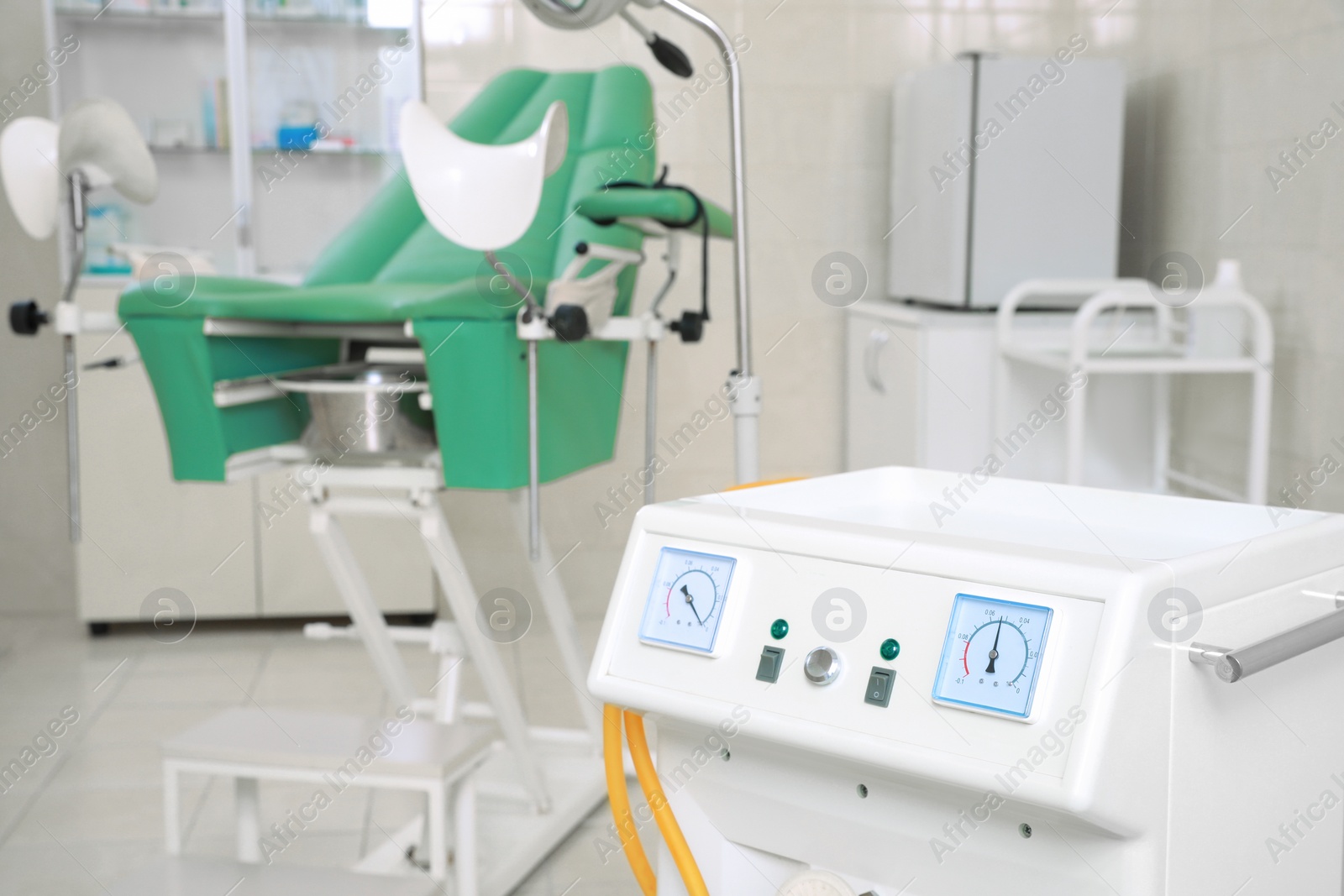 Photo of Examination room with medical aspirator for artificial abortion and gynecological chair in clinic, closeup. Space for text