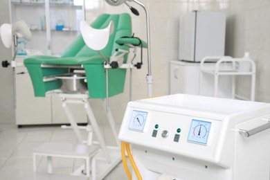 Examination room with medical aspirator for artificial abortion and gynecological chair in clinic, closeup. Space for text