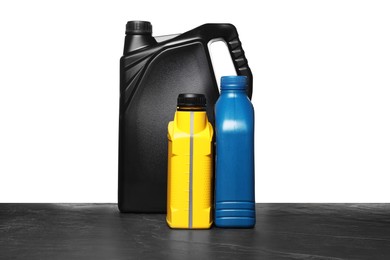 Photo of Motor oil in different canisters on black table against white background