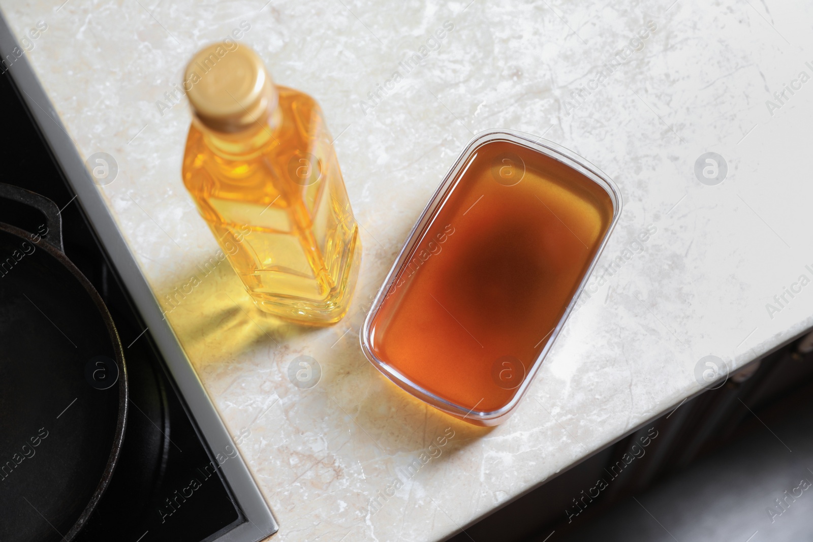 Photo of New and used cooking oil near stove on kitchen counter