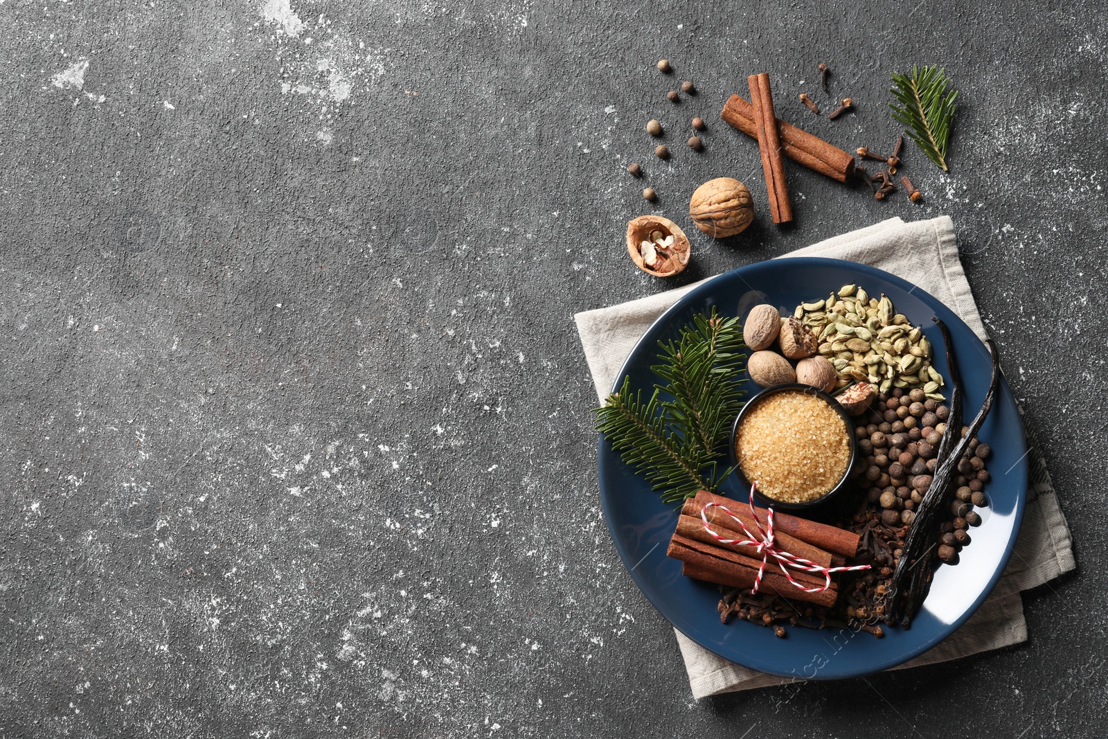 Photo of Different aromatic spices and fir branches on grey textured table, flat lay. Space for text