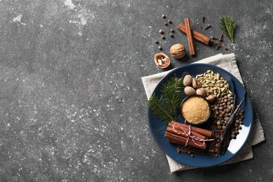Photo of Different aromatic spices and fir branches on grey textured table, flat lay. Space for text
