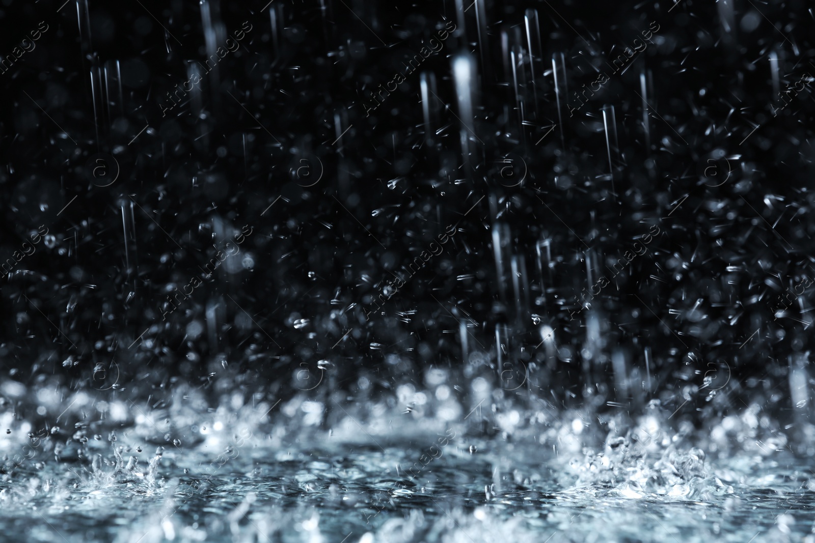 Photo of Heavy rain falling down on ground against dark background