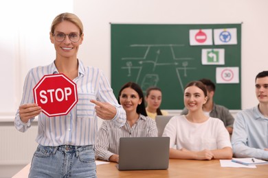 Teacher showing Stop road sign during lesson in driving school