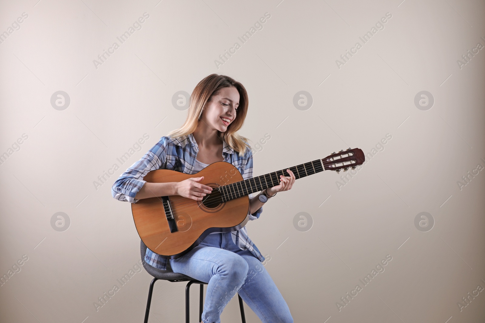 Photo of Young woman playing acoustic guitar on grey background