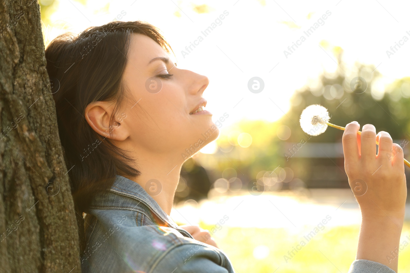 Photo of Young woman with dandelion in park on sunny day. Allergy free concept